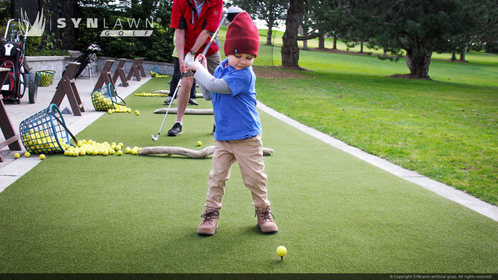 Kid teeing off on artificial golf grass