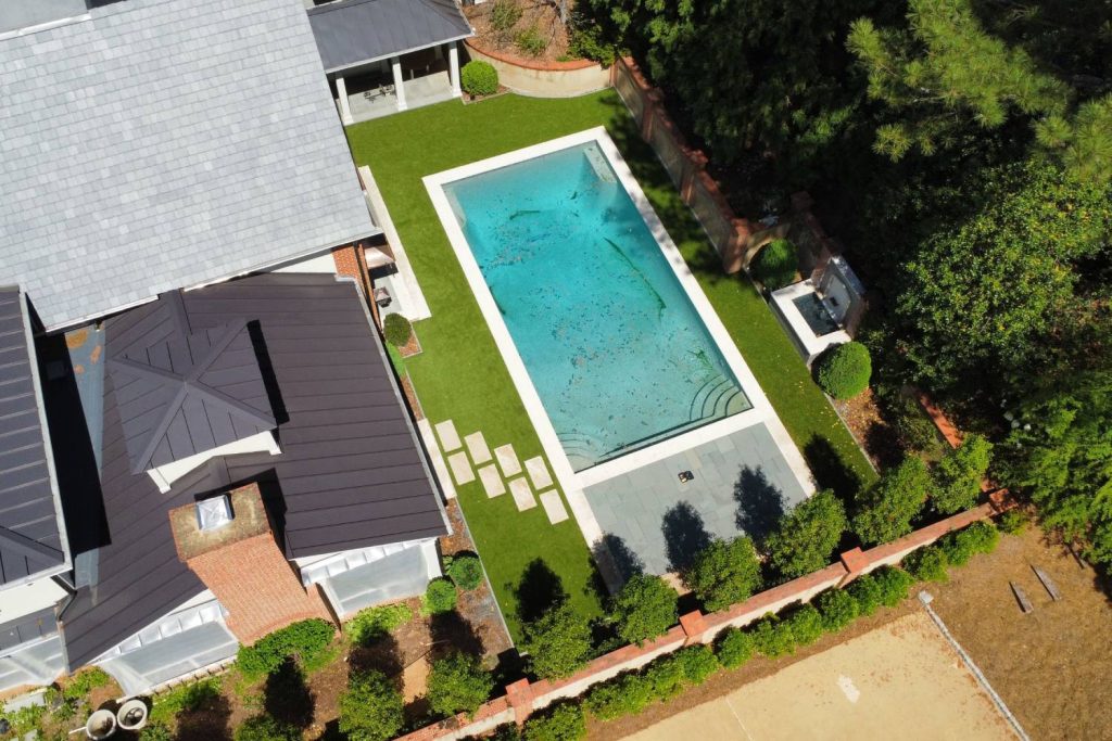 Drone shot of artificial grass backyard with pool
