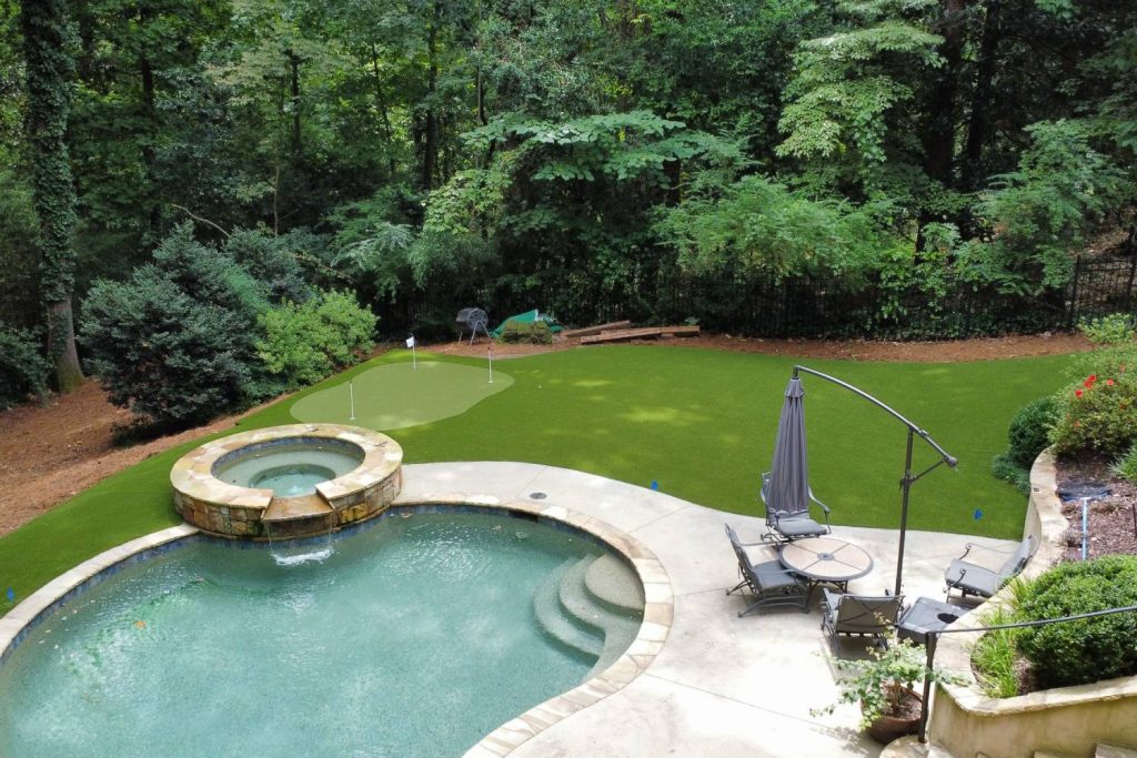 Pool and hot tub with artificial grass backyard and putting green