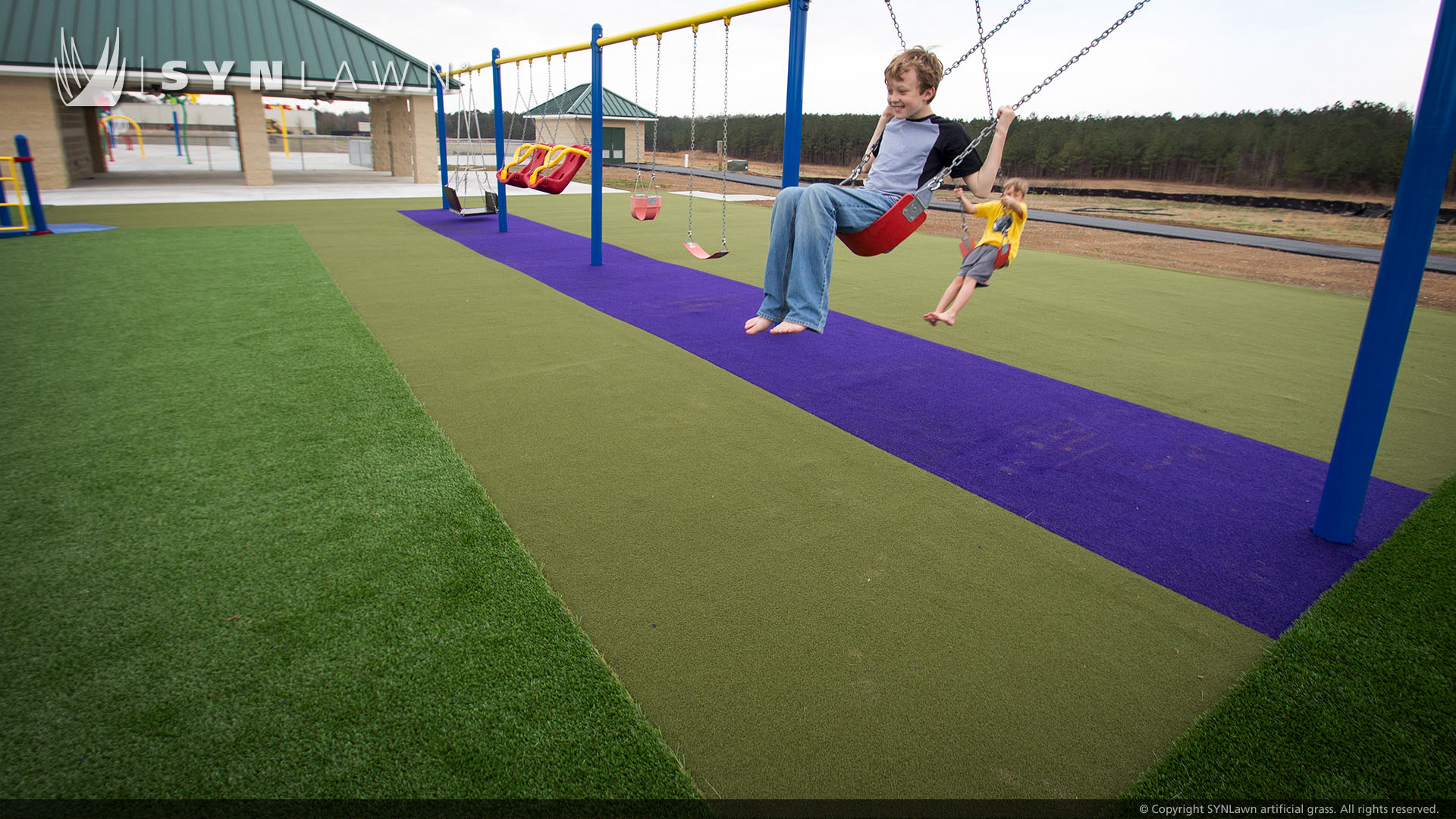 kids playing on swingset on artificial grass